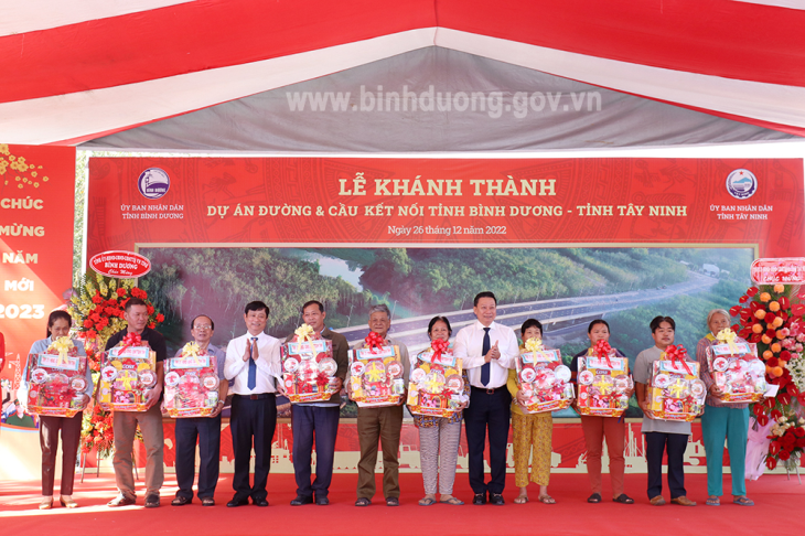 Chủ tịch UBND tỉnh Bình Dương Võ Văn Minh (thứ 4 từ trái qua) và Chủ tịch UBND tỉnh Tây Ninh Nguyễn Thanh Ngọc (thứ 5 từ phải qua) tặng quà cho các hộ dân tích cực phối hợp trong công tác giải phóng mặt bằng để thực hiện công trình